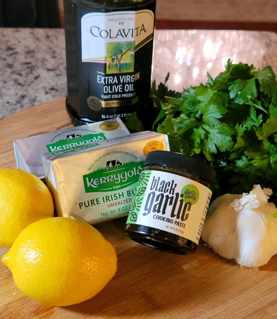 photo of compound Butter ingredients: lemons, kerrygold irish butter, soul to belly black garlic cooking paste, fresh parsley, and extra virgin olive oil